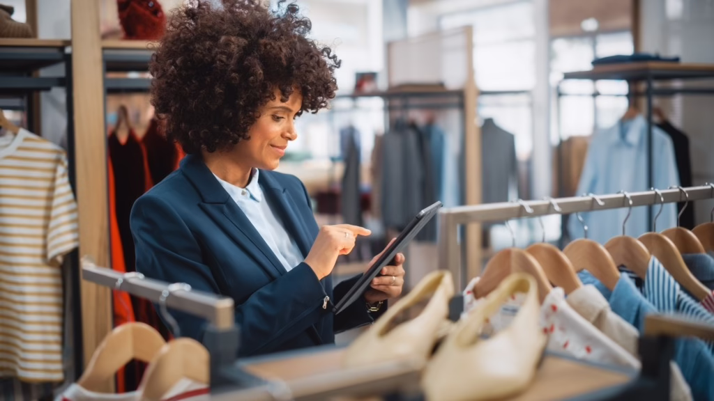A retail store manager using a tablet on the shop floor, illustrating how unified communications technology helps retail businesses streamline staff communication and boost productivity