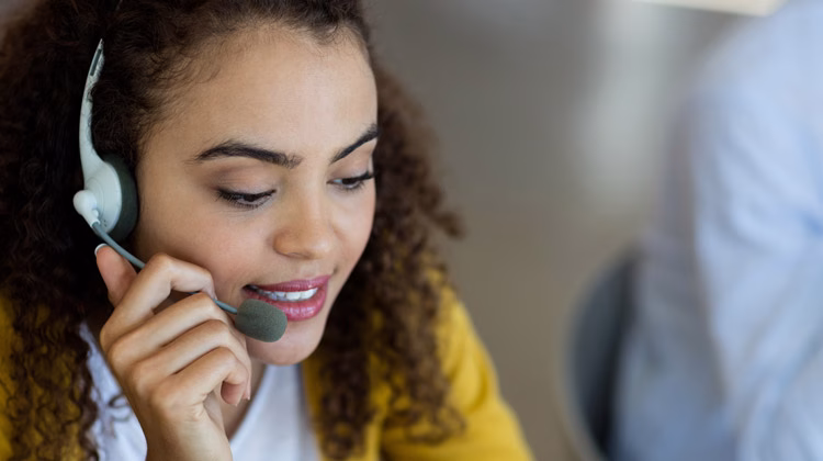 A customer service representative wearing a headset managing sales communications using unified communications technology